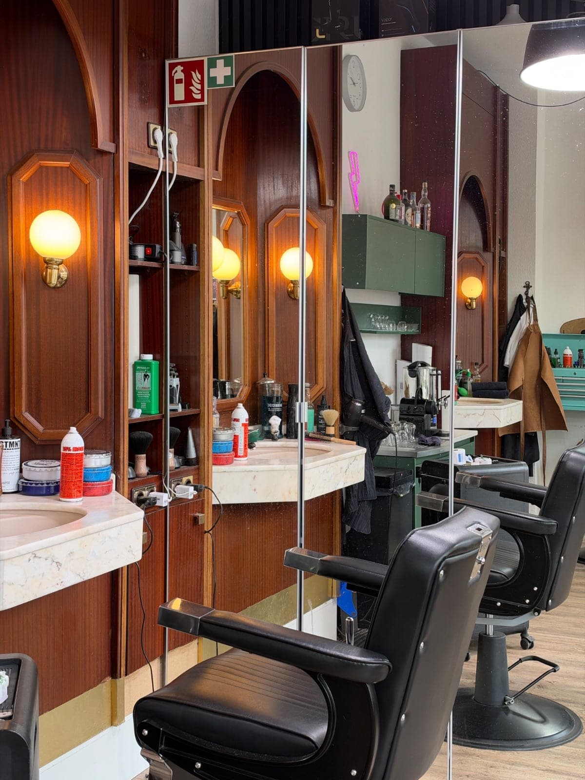 Friseurstühle vor Spiegeln und Waschbecken in Kani's Barbershop